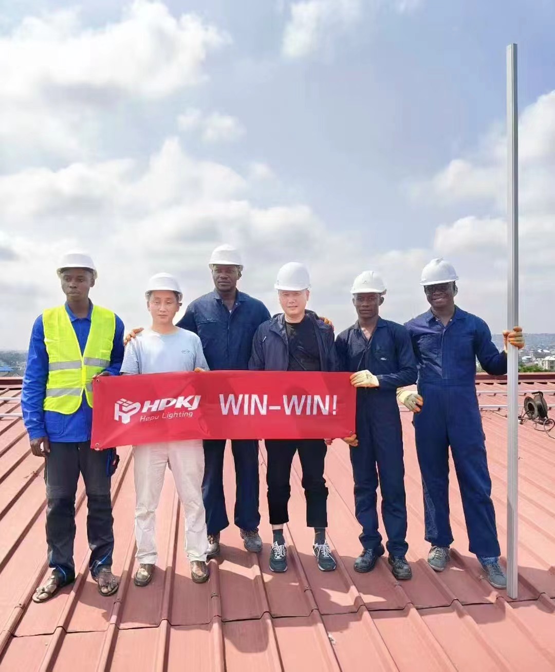 A team of engineers in hard hats reviewing blueprints at a construction site in a foreign country.